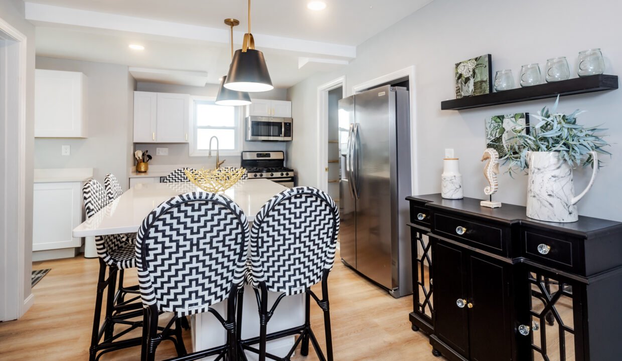A kitchen with black and white stools and a white island.