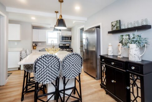 A kitchen with black and white stools and a white island.