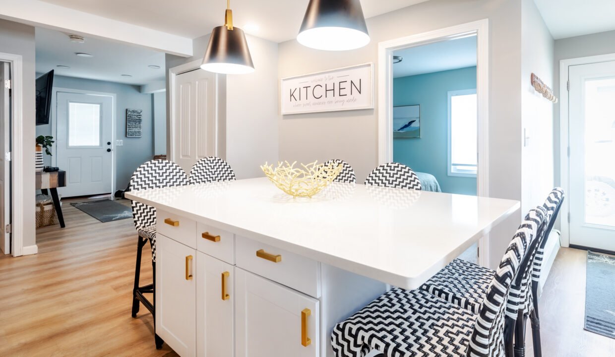 A kitchen with a white island and black chairs.