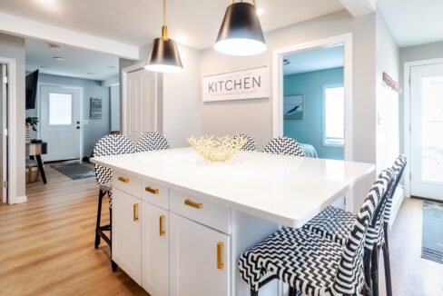 A kitchen with a white island and black chairs.