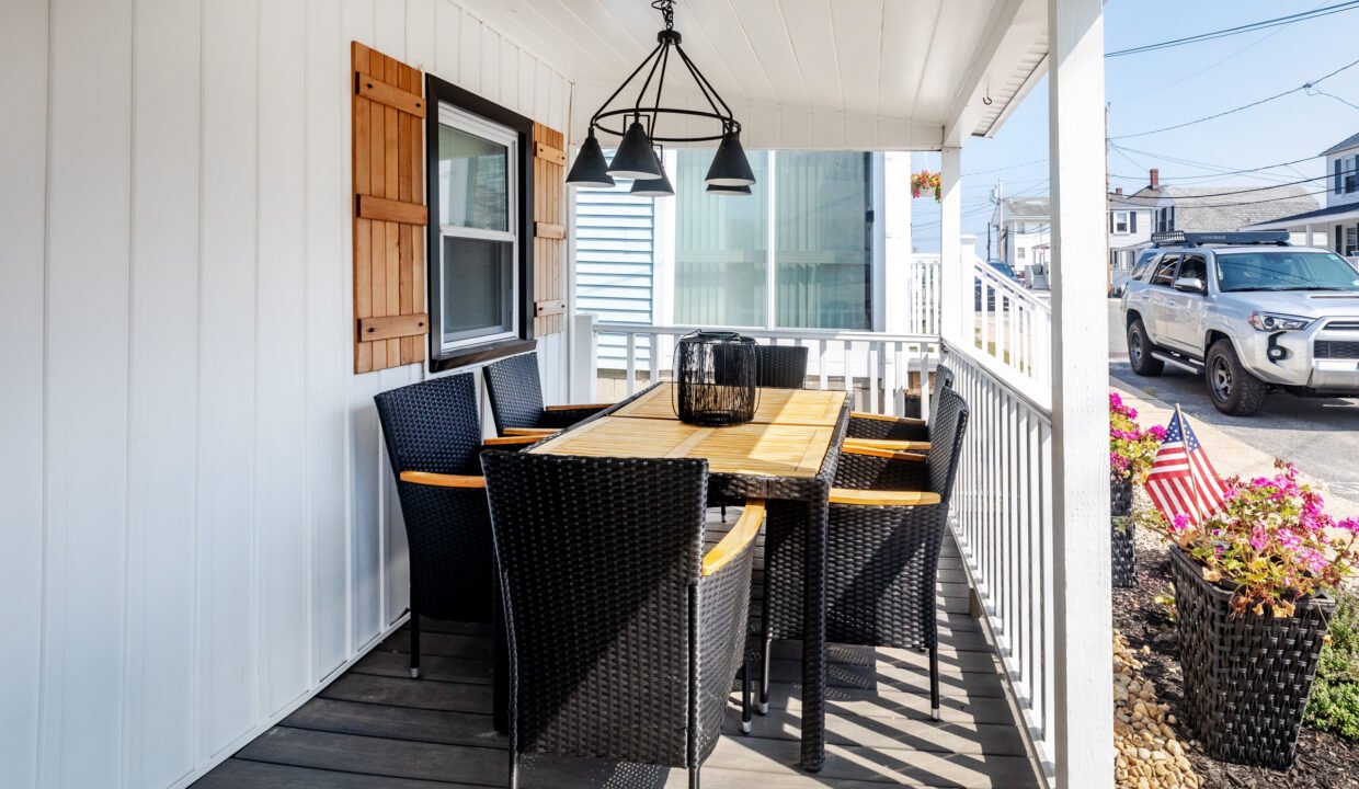 A porch with a table and chairs on it.