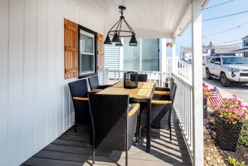 A porch with a table and chairs on it.