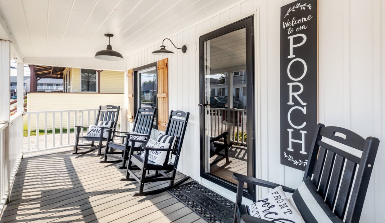 A porch with rocking chairs and a sign.