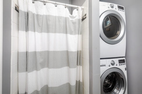 A laundry room with a washing machine and a shower curtain.