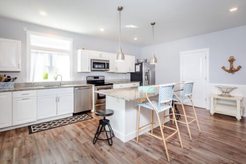 A kitchen with wood floors and a bar stools.