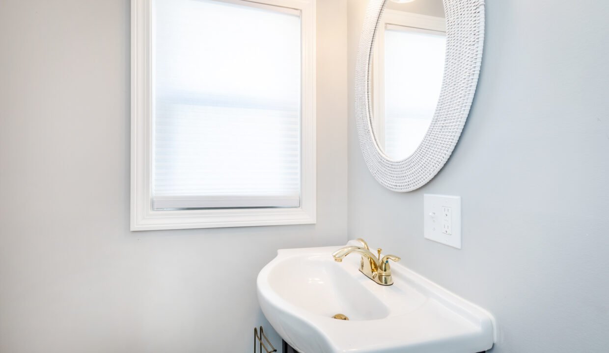 A bathroom with a sink, mirror, and window.