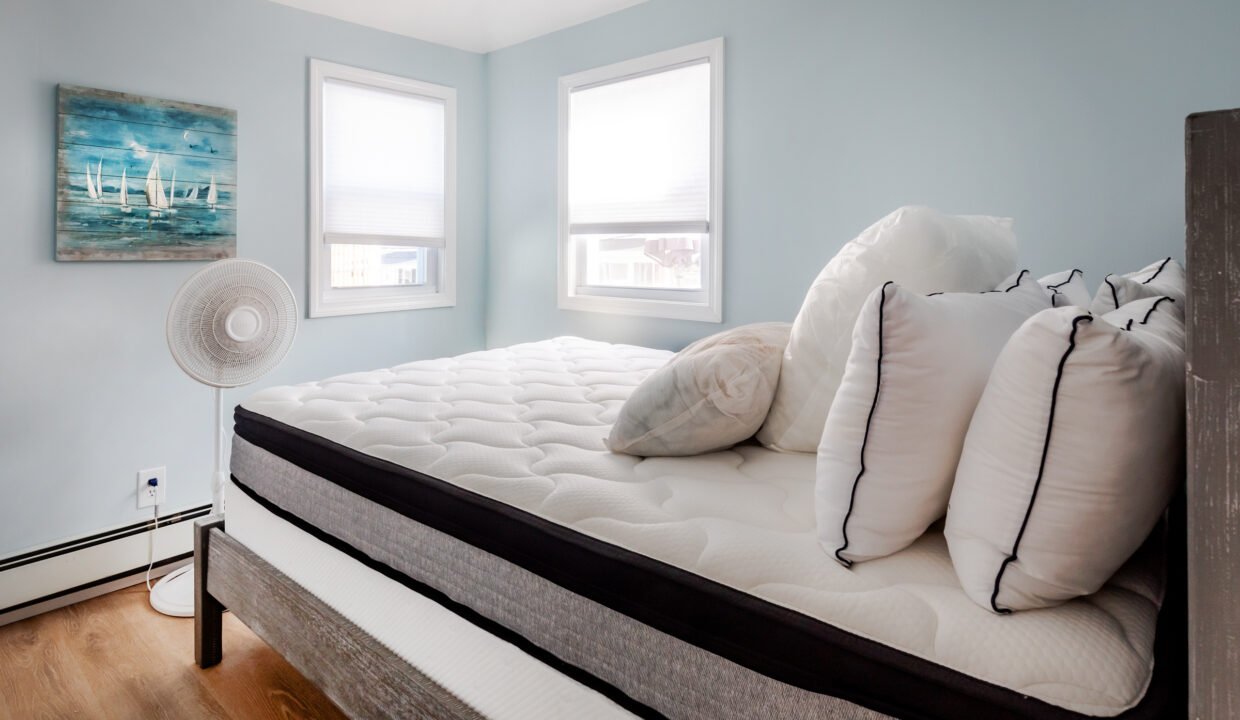 A bed in a bedroom with blue walls and a fan.