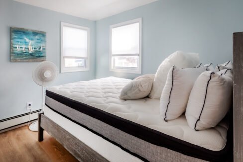 A bed in a bedroom with blue walls and a fan.