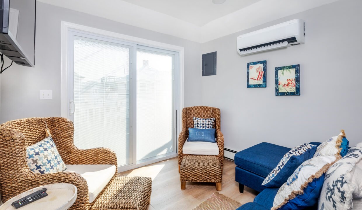 A living room with wicker furniture and an air conditioner.