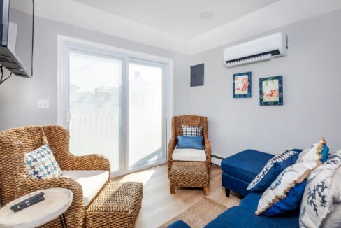 A living room with wicker furniture and an air conditioner.