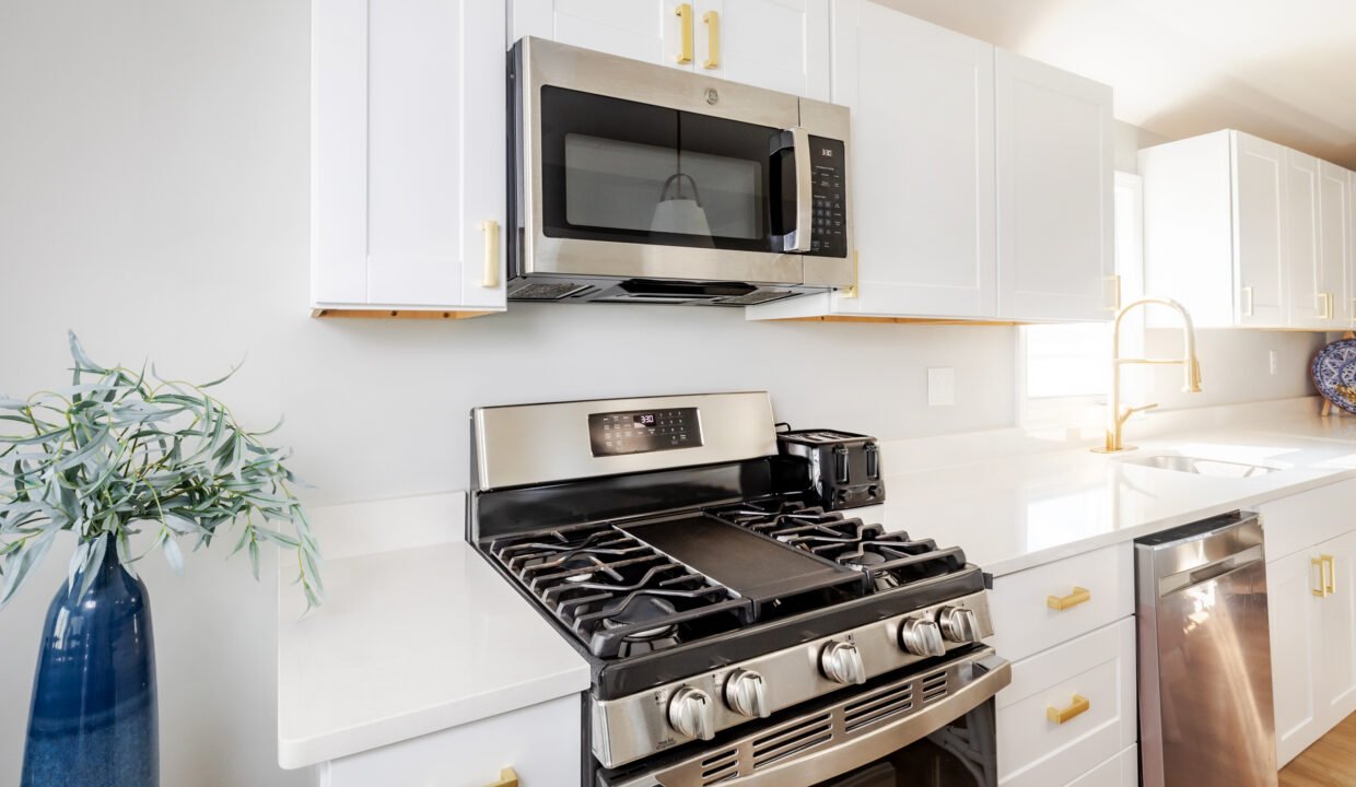 A white kitchen with a stove and microwave.