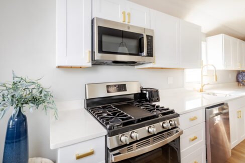 A white kitchen with a stove and microwave.