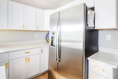 A stainless steel refrigerator in a white kitchen.
