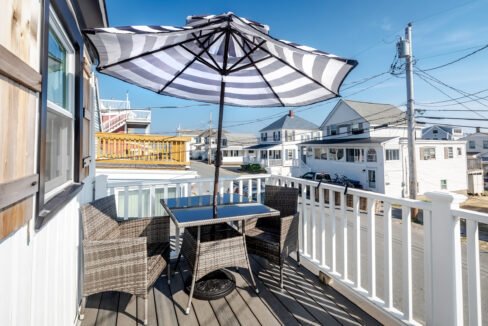 A wicker table and umbrella on a deck with a view of the ocean.