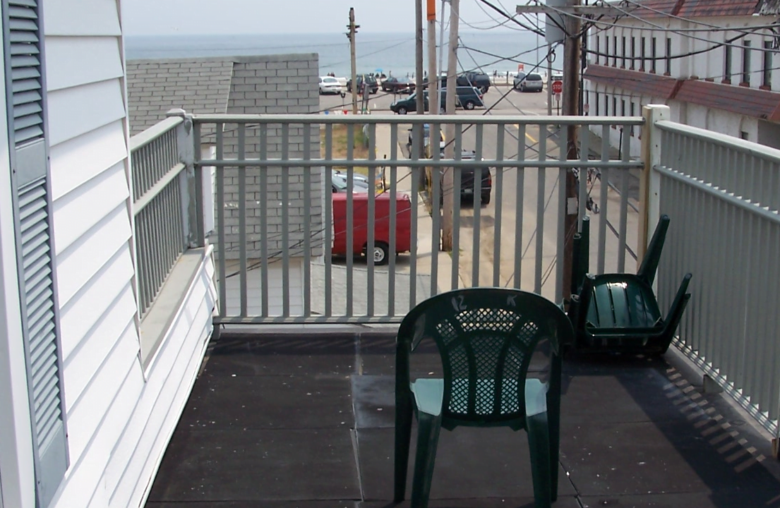 two green chairs sitting on a balcony overlooking the ocean.