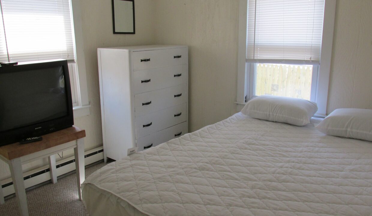 a bedroom with a bed, dresser and television.