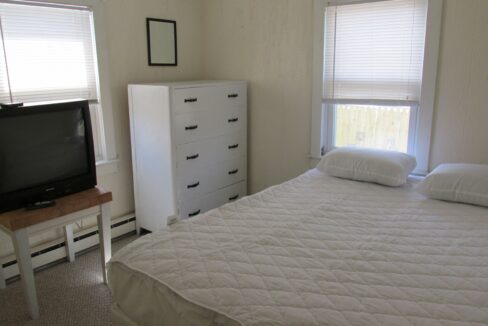 a bedroom with a bed, dresser and television.