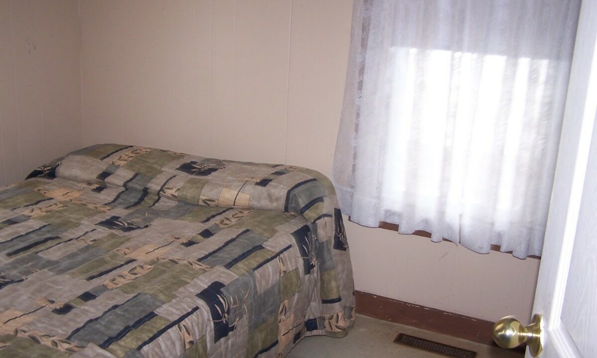 a bed room with a neatly made bed and a window.