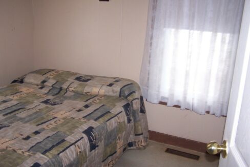 a bed room with a neatly made bed and a window.