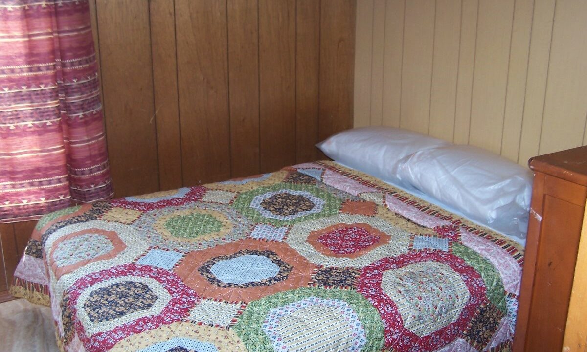 a bed with a colorful quilt on top of it.