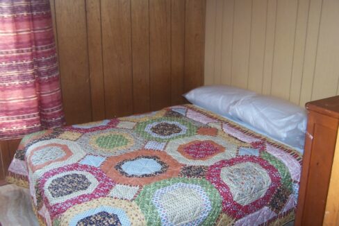 a bed with a colorful quilt on top of it.