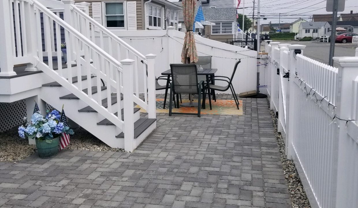 A white patio with chairs and a white fence.