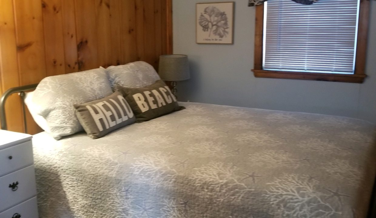 A bedroom with wood paneled walls and a bed.