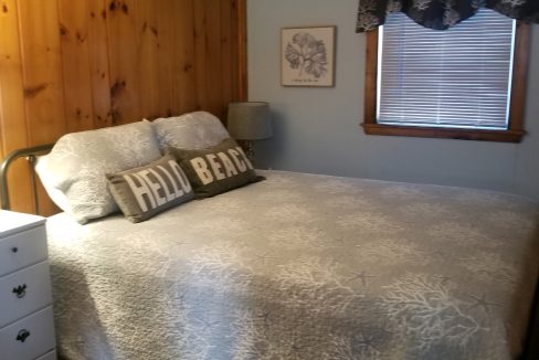 A bedroom with wood paneled walls and a bed.