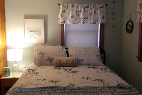 A bedroom with a bed and two windows.