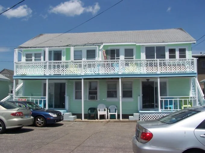 two cars parked in front of a two story house.