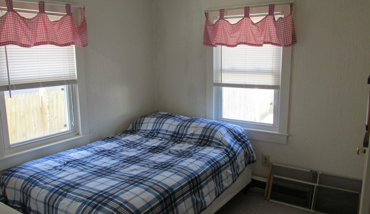 a bedroom with a bed and two windows.