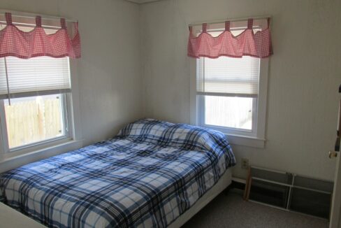 a bedroom with a bed and two windows.