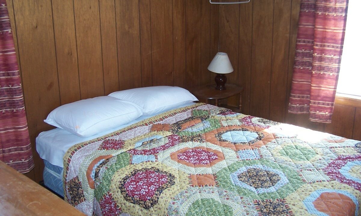 a bed with a quilt on it in a room.