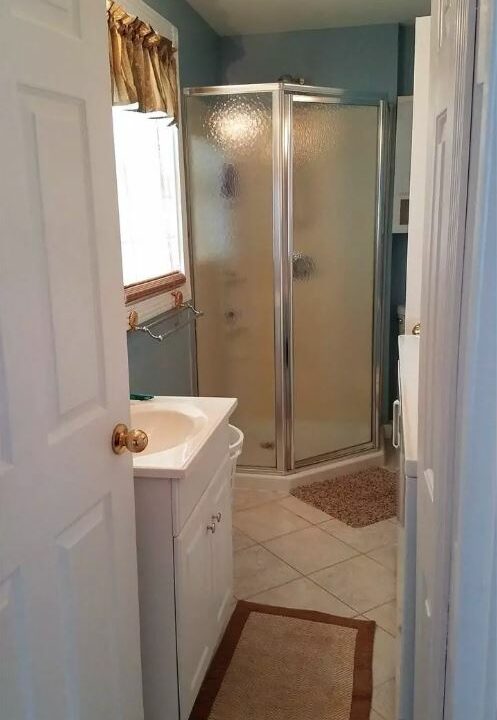 a bathroom with a walk in shower next to a sink.