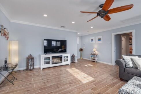 a living room with a ceiling fan and a television.