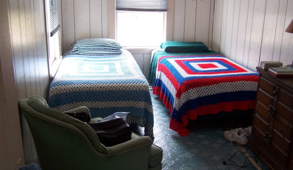 a bedroom with two beds and a chair.