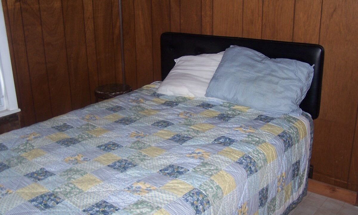 a bed with a blue and yellow quilt on it.