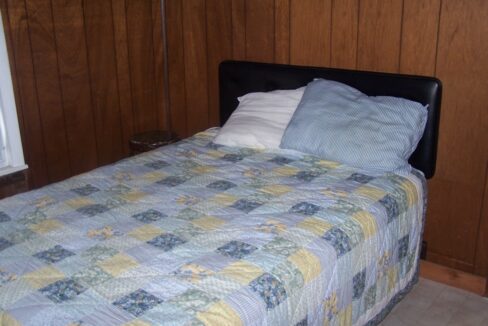 a bed with a blue and yellow quilt on it.