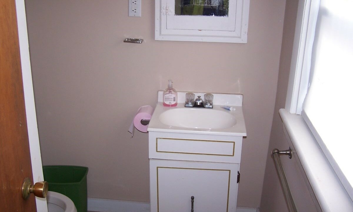 a bathroom with a sink, toilet and a window.