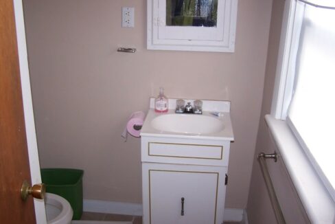 a bathroom with a sink, toilet and a window.