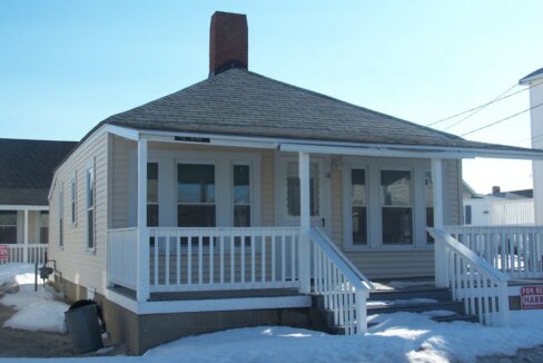 a small house with a porch and a porch covered in snow.