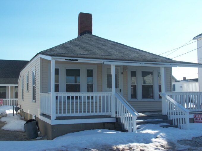 a small house with a porch and a porch covered in snow.