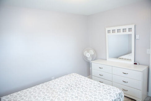 a bedroom with a bed, dresser and mirror.