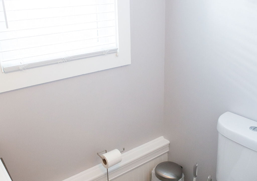 a white toilet sitting next to a window in a bathroom.