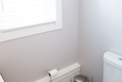 a white toilet sitting next to a window in a bathroom.