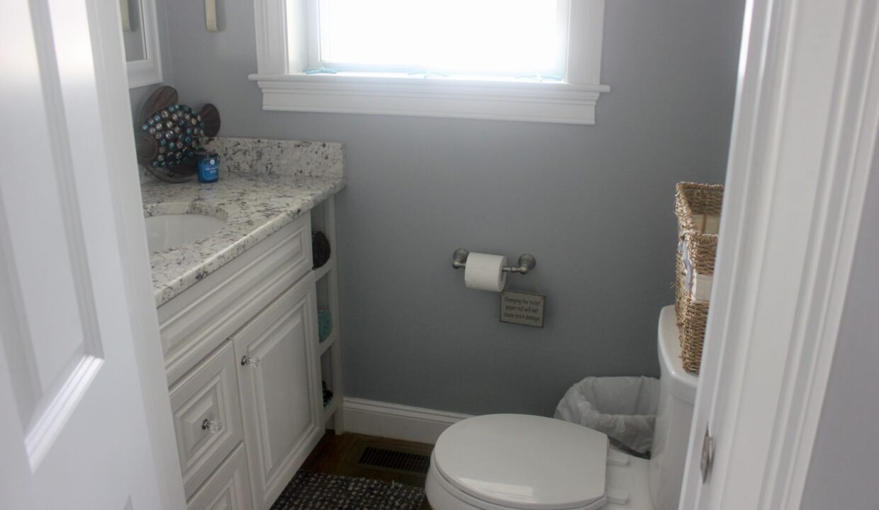 a white toilet sitting under a window in a bathroom.