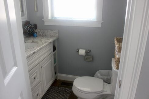 a white toilet sitting under a window in a bathroom.