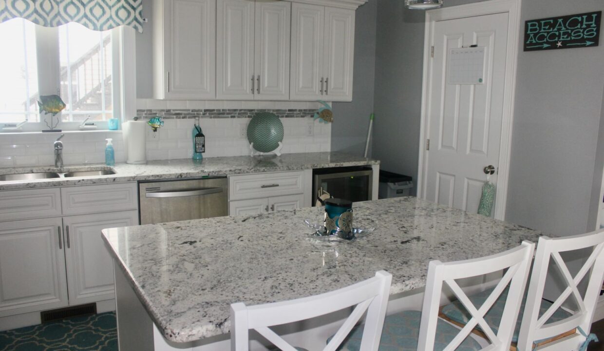 a kitchen with a marble counter top and white cabinets.