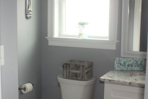 a white toilet sitting in a bathroom next to a window.