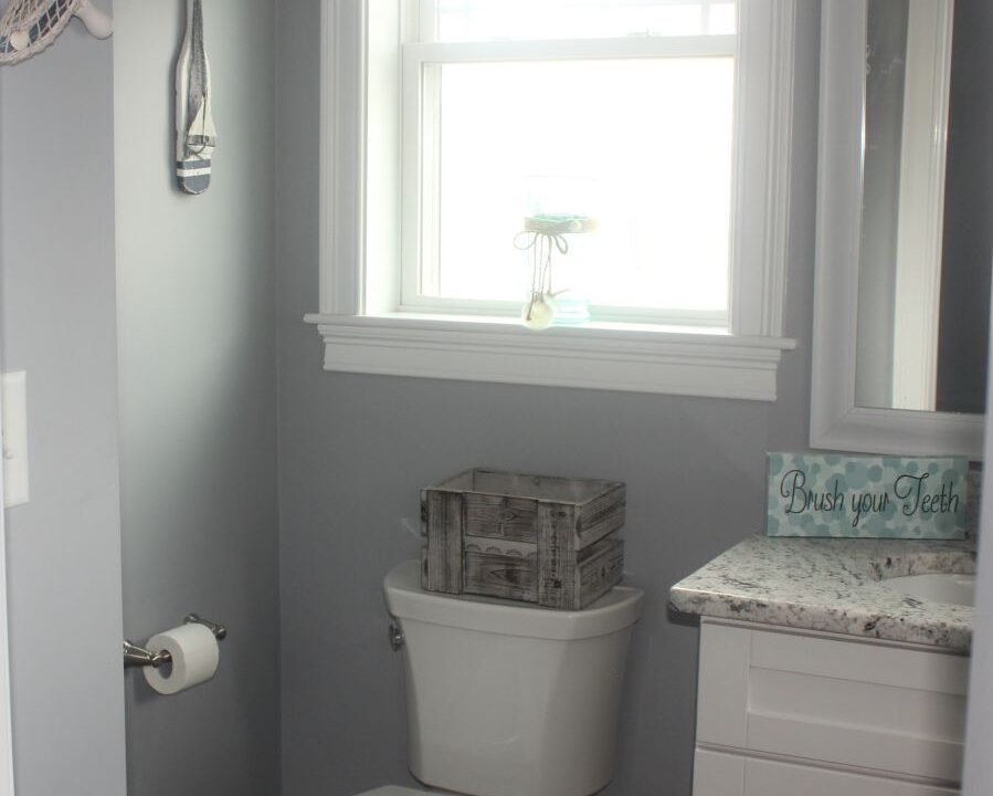 a white toilet sitting in a bathroom next to a window.